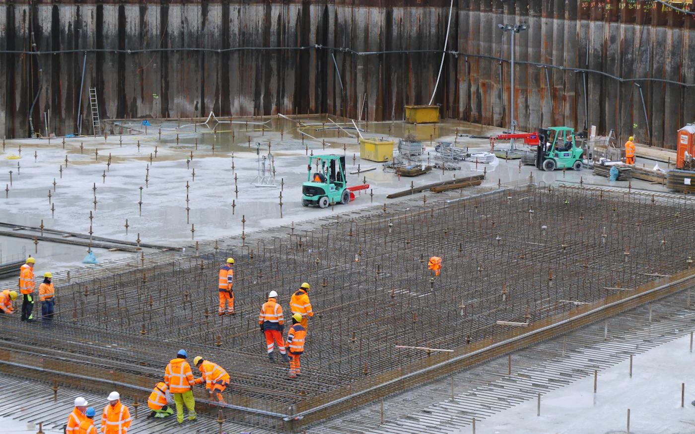 A large civil site with crews working across a poured deck.