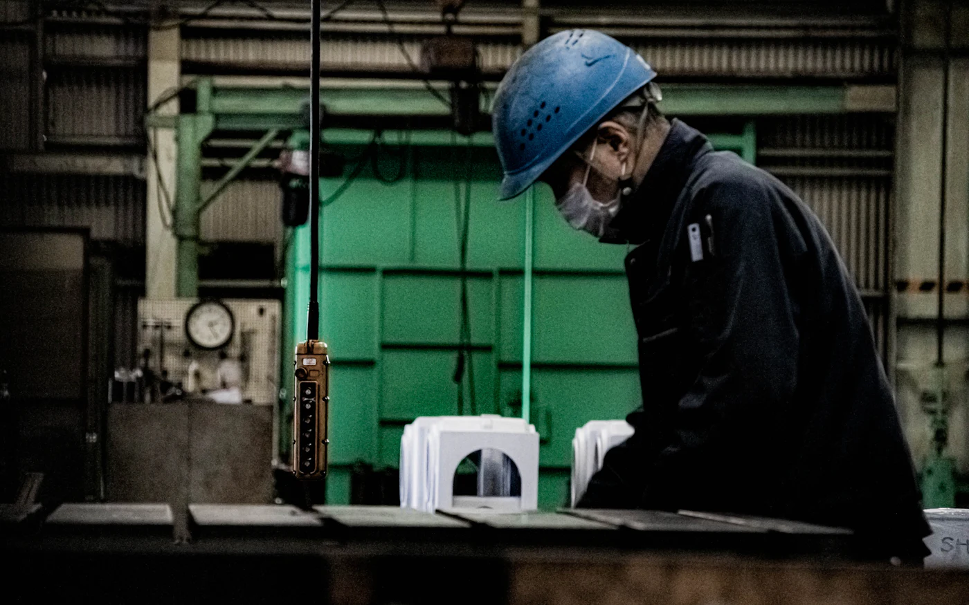 A worker in a hard hat operating machinery on a shop floor.